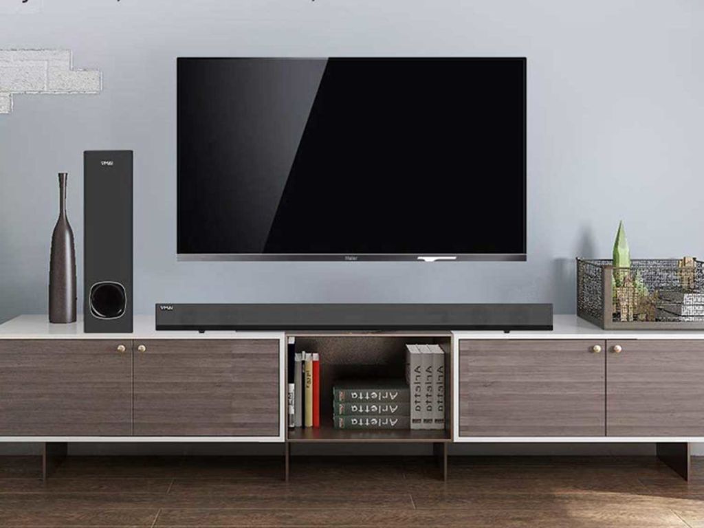 Sound bar sitting on console under a TV.