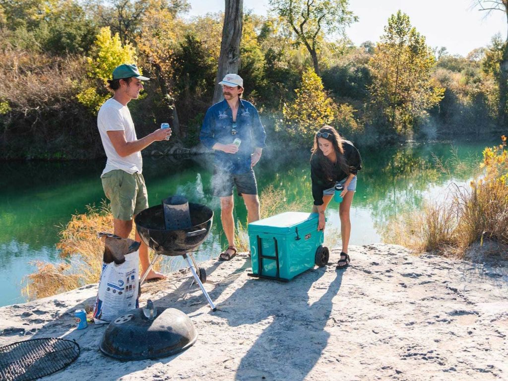 A group of people enjoy drinks by the cooler.