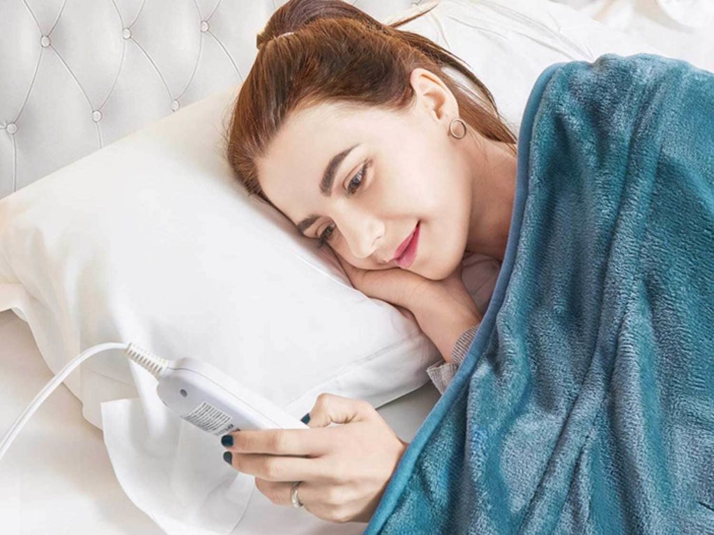 Woman in bed adjusting her heated blanket