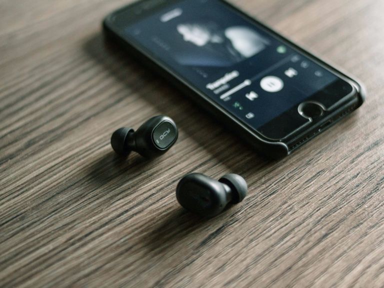 Wireless earbuds next to a smart phone.