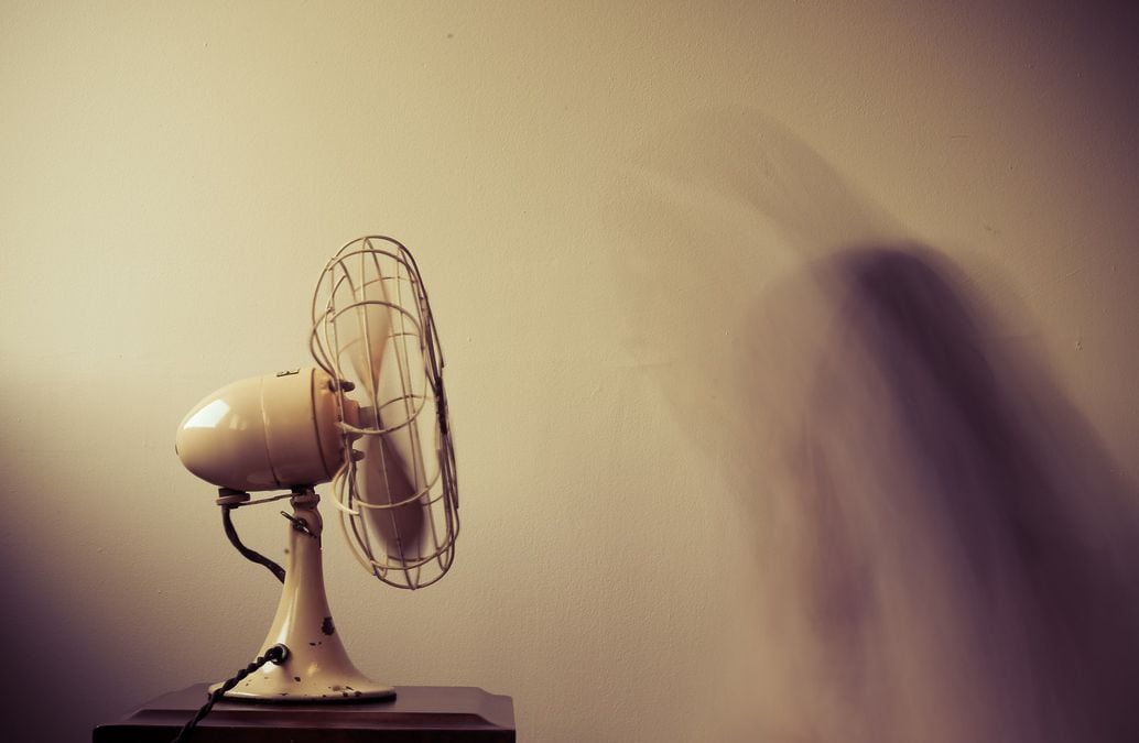 An antique fan blowing while sitting on a desk.