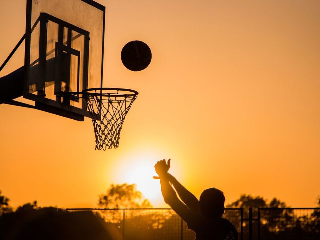 Shooting basketball with the sun setting.