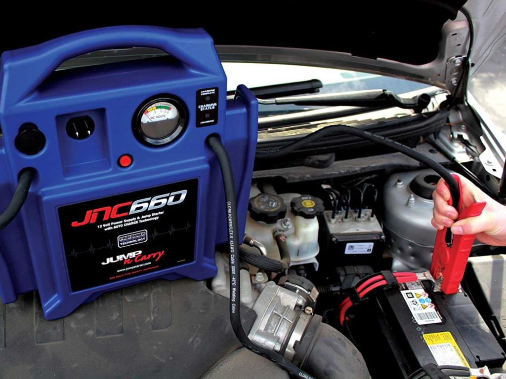 Man using a jump starter kit on his car battery.