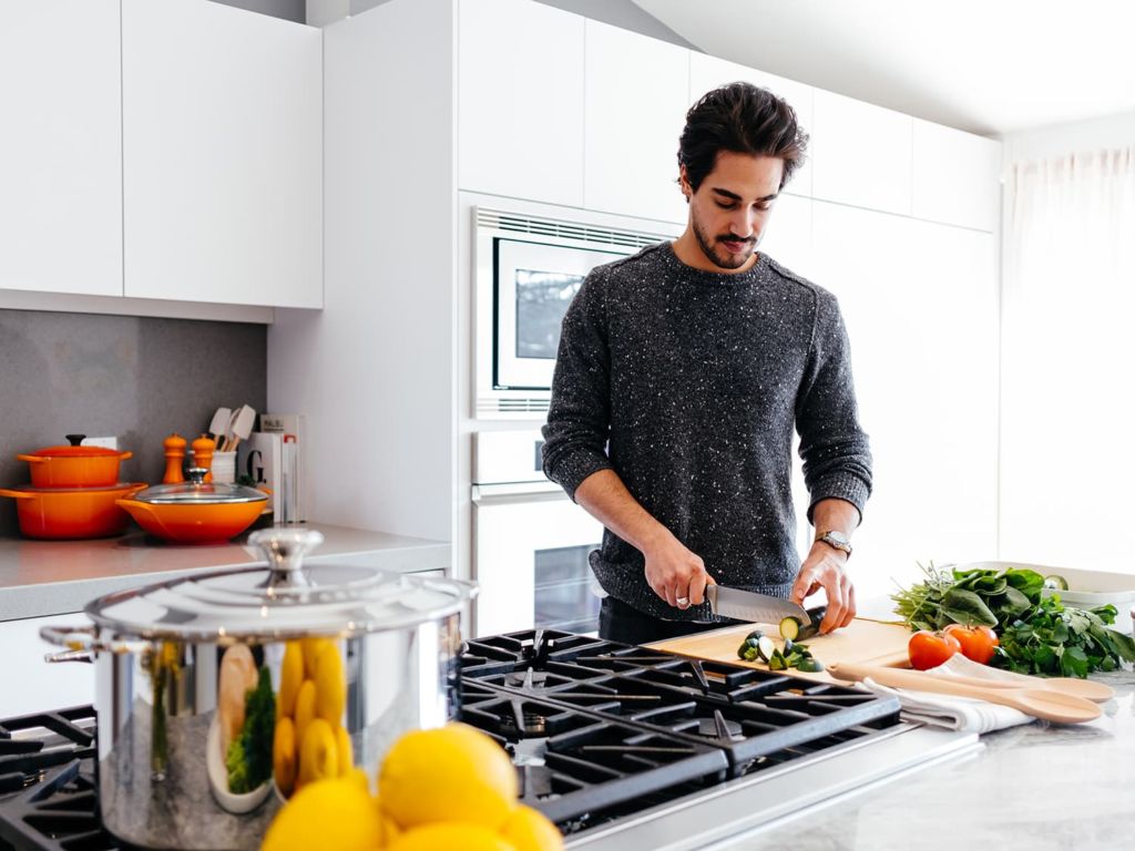 Man in a kitchen slicing vegetables