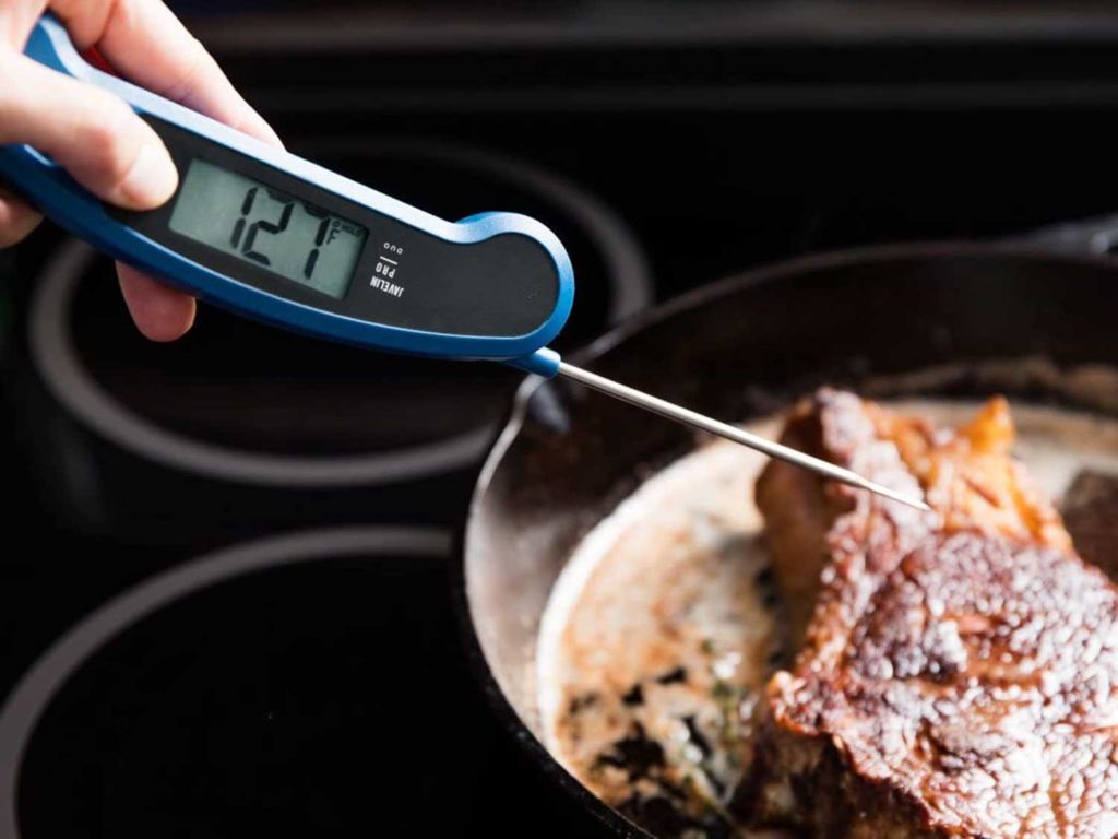 Meat thermometer checking a steak