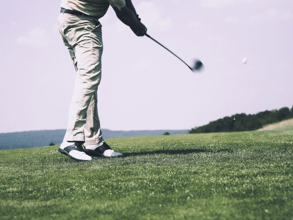 Man wearing golf shoes on a course.