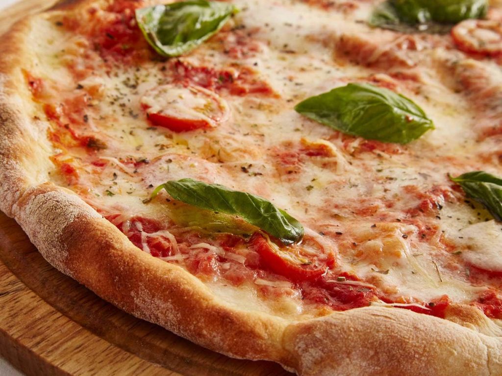 Pizza fully cooked with cheese and basil.