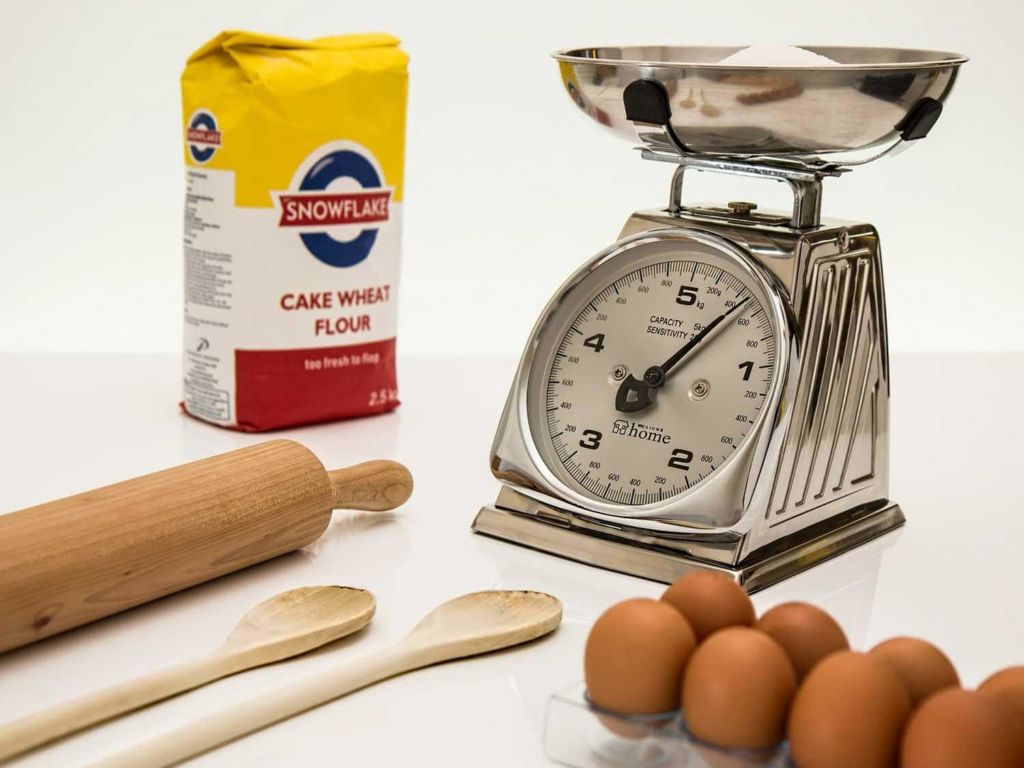 Food scale next to eggs and flour