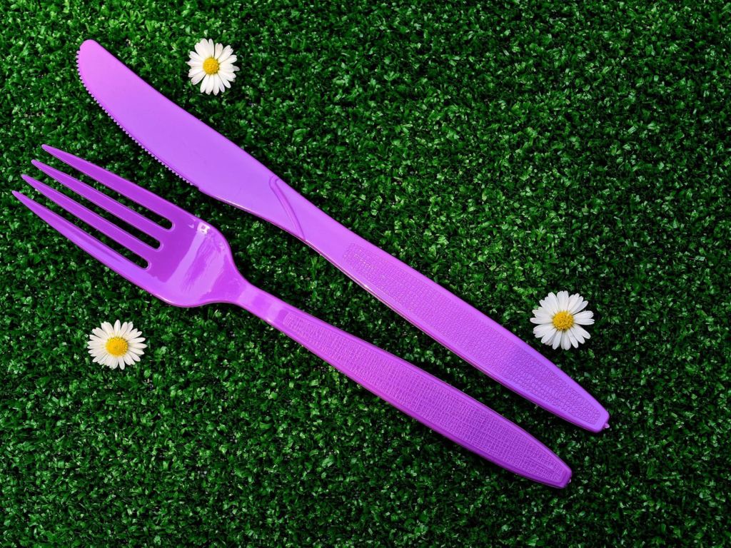 Purple utensils on a grassy surface.