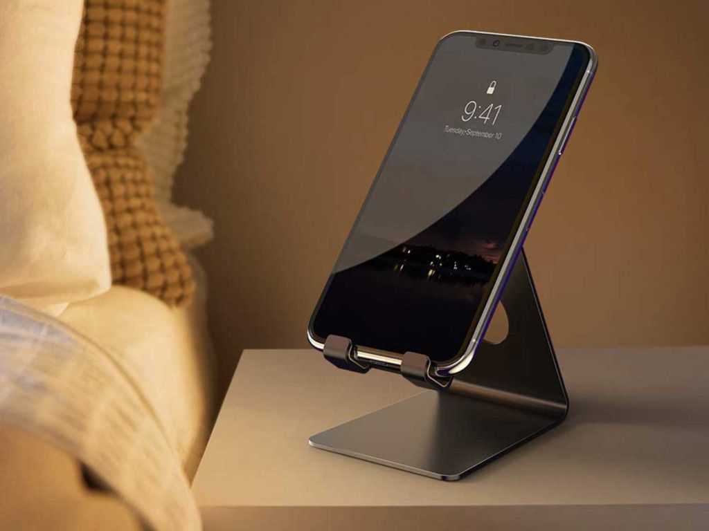 Phone on a stand next to a bed.