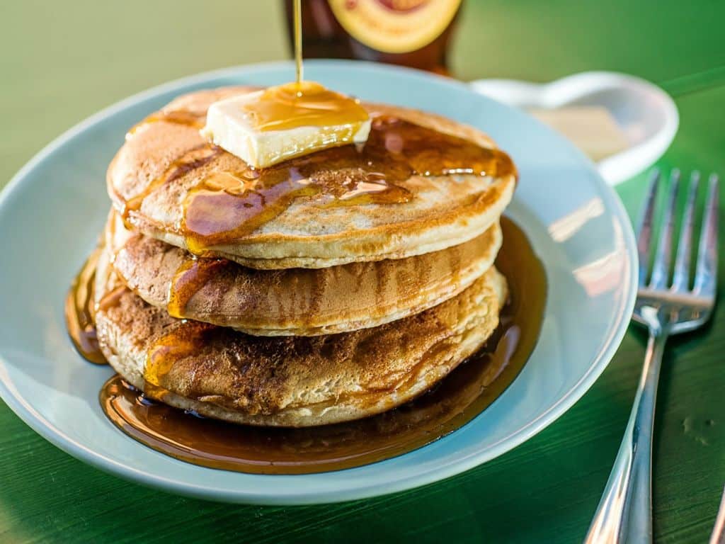Thick pancakes with syrup being poured on them.