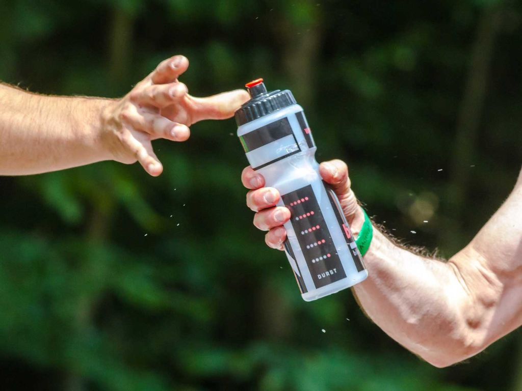 Two men sharing a water bottle outside