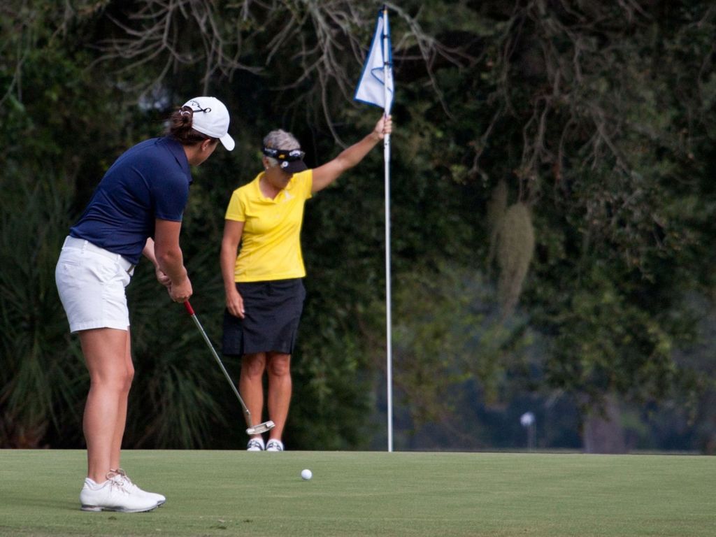 Woman golfer putting with golf shoes