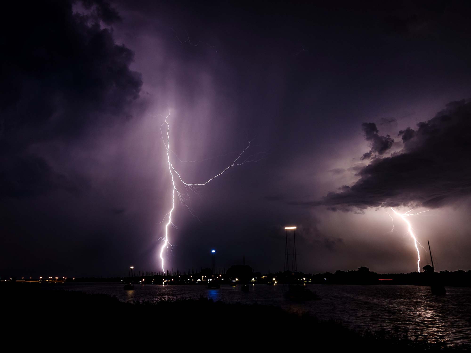 Lighting striking the surface of a body of water at night.