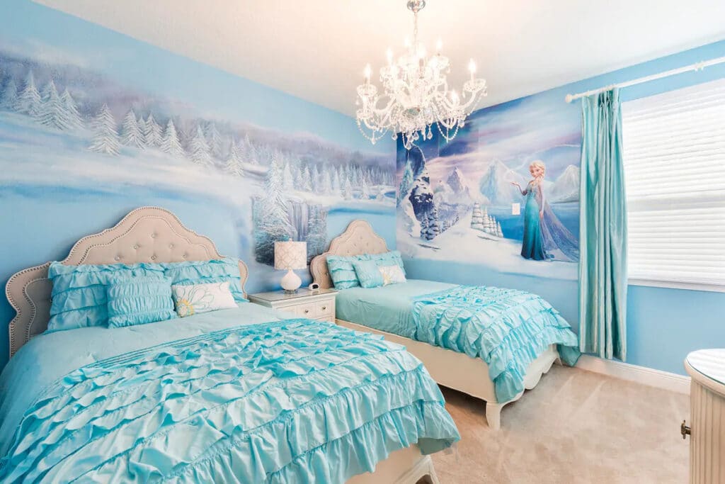A bedroom with two beds decorated in the style of Disney's Frozen. Light blue bedding, and white, make up a cool color scheme.