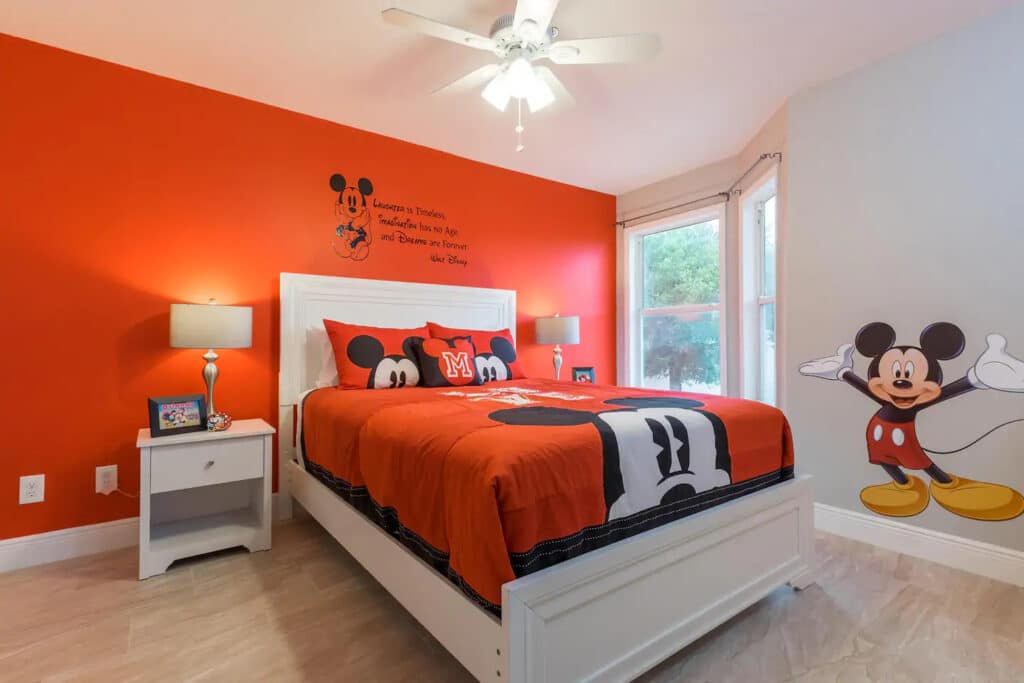 A bedroom decorated in red, white, and black to match the color scheme of the Micky Mouse bedding and wall art.