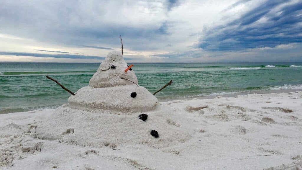 A sand snowman rests on a Florida beach.
