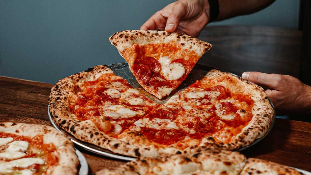 Handing holding a slice of pizza